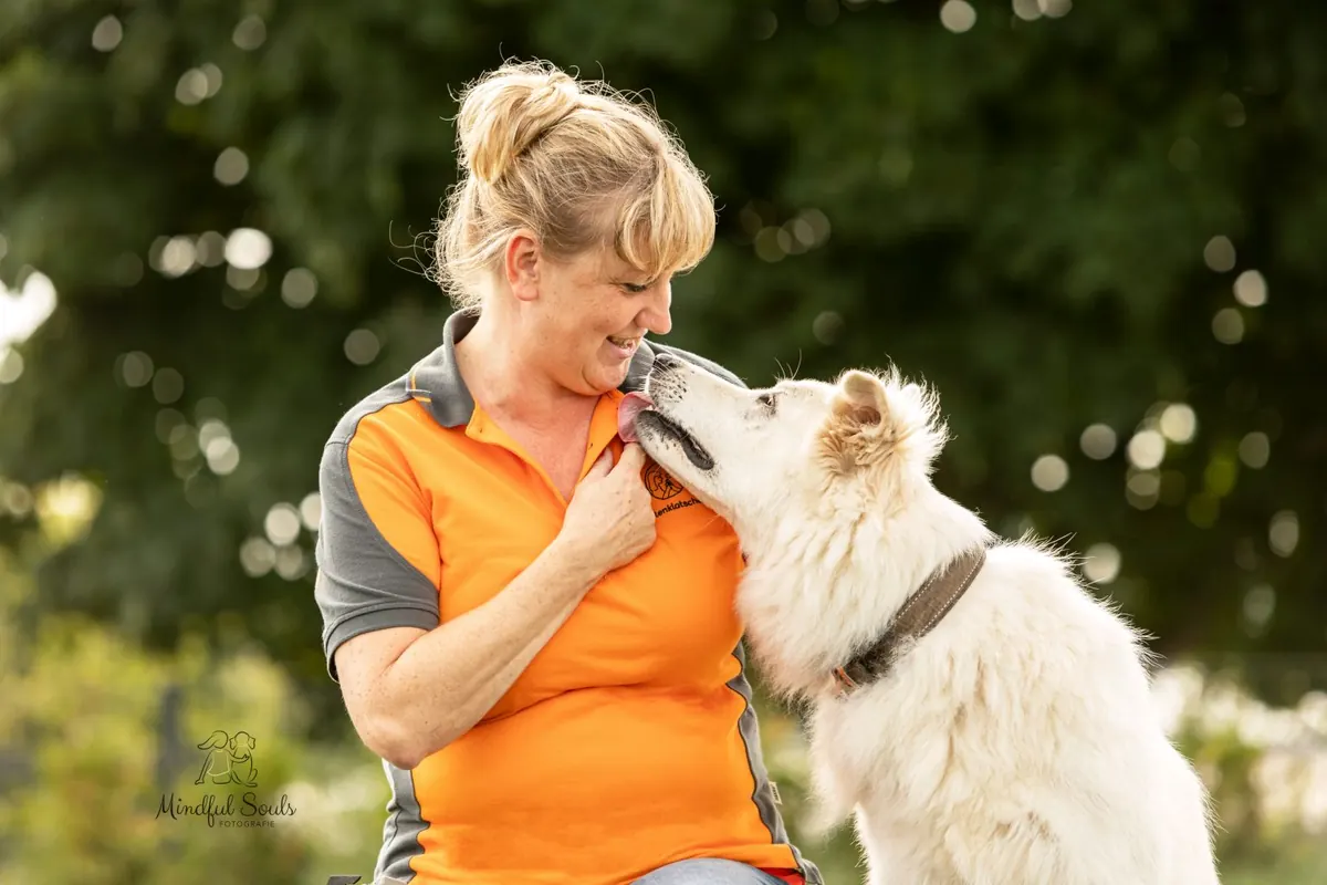 Birgit Prager lacht, während der weiße Schäferhund ihr das Gesicht abschleckt