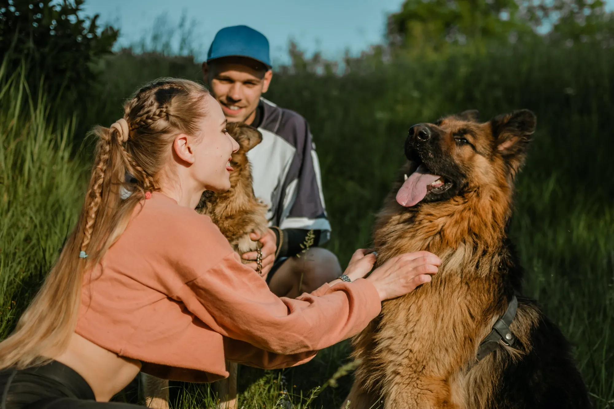 Paar kuschelt draußen mit seinem jungen Schäferhund